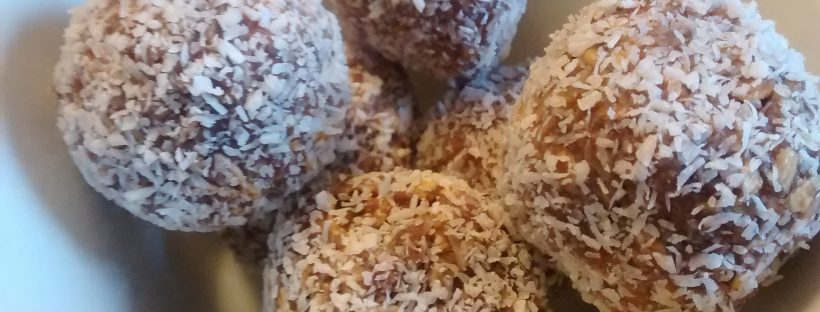 Snowball Cookies rolled in flaked coconut and piled in a white ceramic bowl